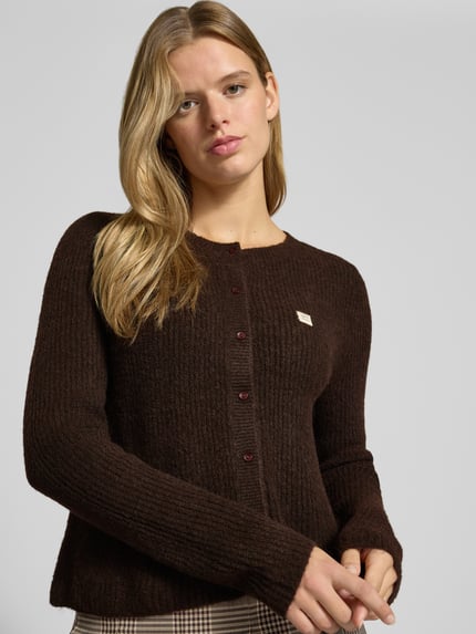 Frauenmodel trägt Cardigan mit Label-Patch von ONLY in unifarbener, gestrickter Optik mit Rundhalsausschnitt, Nahaufnahme Oberkörper.
