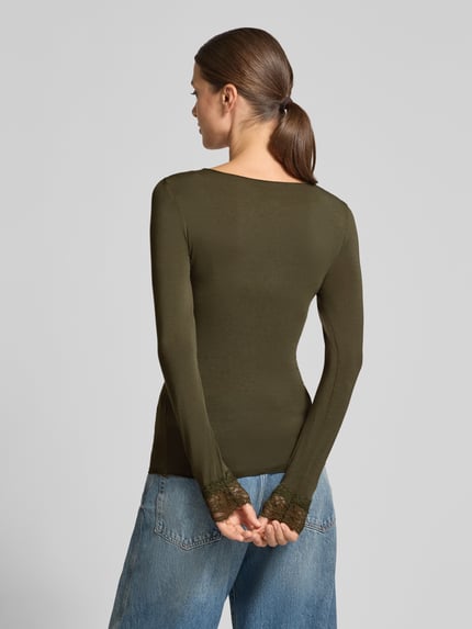 Frauenmodel trägt olivgrünes Slim Fit Langarmshirt aus Modal-Mix mit Woll-Anteil Modell 'SKYE' von VERO MODA, glatte Struktur, Ganzkörperansicht Rückansicht. Damen Langarmshirt.