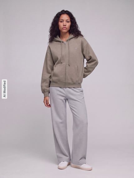 Frauenmodel trägt Regular Fit Sweatjacke aus Baumwoll-Mix von Levi's® in Olive mit schlichter Struktur zu hellgrauer Hose, Ganzkörperansicht von vorne, KI-modifiziertes Bild.