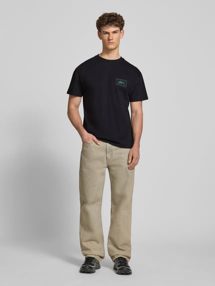 Männermodel trägt Regular Fit T-Shirt mit Logo-Print von BLKVIS in Schwarz aus Reine Baumwolle, Rundhalsausschnitt, Ganzkörperansicht von vorne. Rückenlänge bei Größe M: 67 cm.