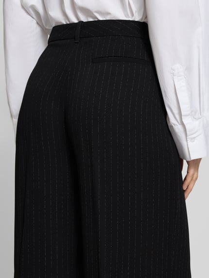 Frauenmodel trägt Weite Hose aus reiner Viskose Modell 'TIANA4' von BOSS mit Nadelstreifen-Muster und angedeuteter Gesäßtasche, Detailaufnahme Rückansicht.