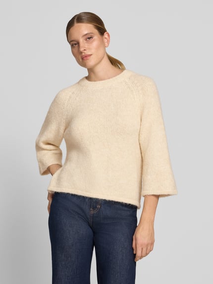 Vrouwenmodel draagt gebreide pullover met Raglanmouwen van FREE/QUENT in licht beige, materiaalmix met wol, recht model, ronde hals, ruglengte maat S 54 cm, mouwlengte maat S 50 cm, voorkant bovenlichaam close-up.