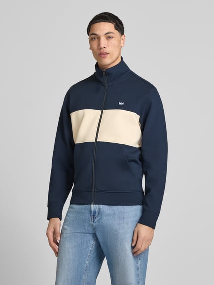 Mannelijk model draagt sweatjack met labelpatch model 'KOSTER' van Helly Hansen van katoenmix met stretch, recht model, opstaande kraag, ritssluiting, zij-steekzakken, ruglengte bij maat M 67 cm, mouwlengte 66 cm, donkerblauw met beige inzet, vooraanzicht bovenlichaam