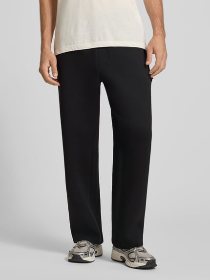 Männermodel trägt Regular Fit Sweatpants aus Material-Mix Modell 'BILL LEGACY' von JACK & JONES in Schwarz, elastischer Bund, Eingrifftaschen, Ganzkörperansicht von vorne, Herren Sweatpants, KI-modifiziertes Bild.