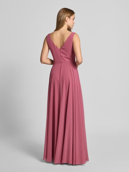 Frauenmodel trägt Maxikleid aus Chiffon in Wickel-Optik von TROYDEN COLLECTION in Altrosa, A-Linie, fließende Textur, Ganzkörperansicht Rückansicht.