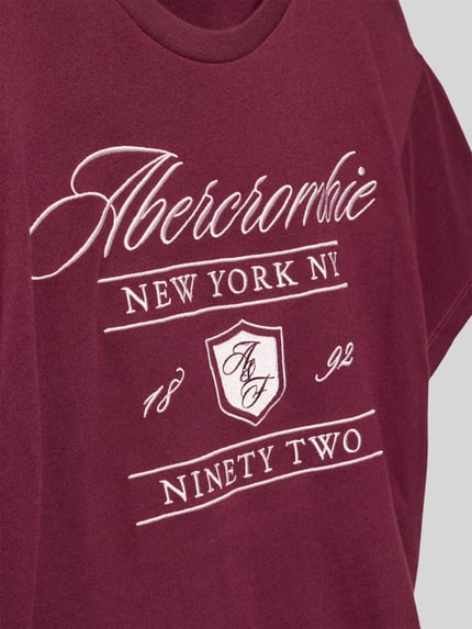 Mädchen trägt Regular Fit T-Shirt mit Logo-Stitching von Abercrombie&Fitch, Baumwoll-Mix in Bordeaux mit weißem Aufdruck, Nahaufnahme Oberkörper