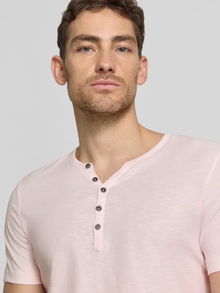 Męski model nosi T-Shirt mit V-Ausschnitt und Knopfleiste von MCNEAL z bawełny, krój regular fit, jasnoróżowy, z przodu, zbliżenie na górę.