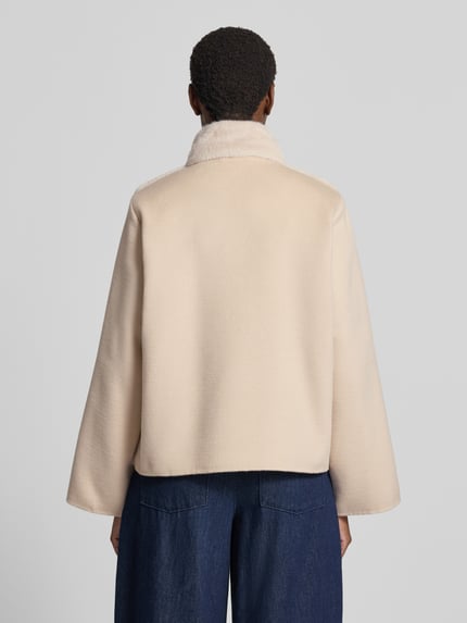 Frauenmodel trägt Jacke mit Viskose-Anteil Modell 'BALIA' von EMME in hellem Beige mit Kunstfellbesatz, Steppnähten, lockerer Passform, Ganzkörperansicht Rückansicht.