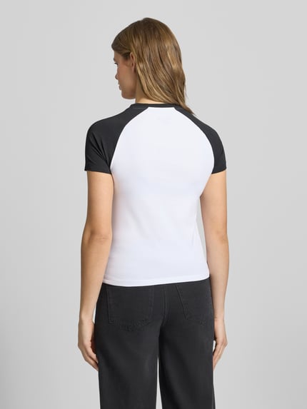 Vrouwenmodel draagt Slim Fit T-shirt met ronde hals en logo van Guess Jeans in zwart-wit, mix van katoen en elastaan, ruglengte maat S 53 cm, slim fit. Ganzkörperansicht Rückansicht.