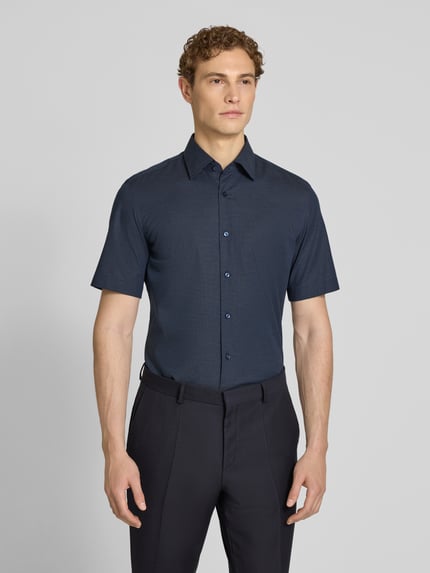 Männermodel trägt Regular Fit Businesshemd aus Baumwoll-Mix Modell 'KENT SH C1' von BOSS, blaues Allover-Muster, Ganzkörperansicht von vorne.