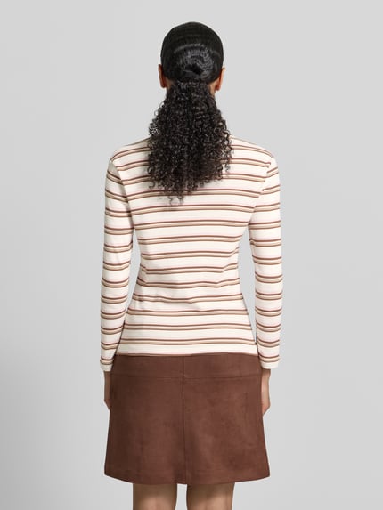 Frauenmodel trägt Slim Fit Rollkragenpullover aus reiner Baumwolle von s.Oliver RED LABEL, efekt: wzór w paski, wyhaftowane logo, dżersej, brązowe i kremowe pasy, długi rękaw, widok całej sylwetki z tyłu.