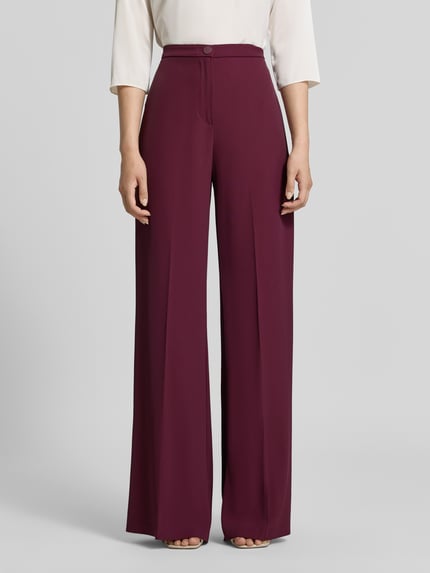 Vrouwenmodel draagt Wide Leg Stoffhose mit Knopfverschluss van Rinascimento in donker bordeaux, Materiaalmix met stretch, Bandwijdte maat S 40 cm, Binnenbeenlengte 85 cm, wide leg fit, knoopsluiting en ritssluiting, gladde textuur, Ganzkörperansicht von voren.