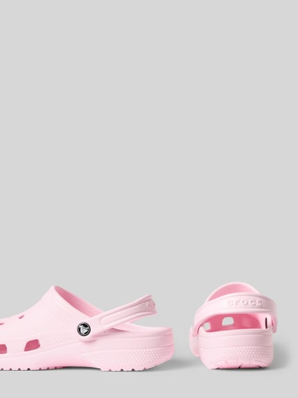 Produktfoto, Clogs mit Label-Detail von Crocs in zartem Rosa, abgerundete Spitze, Schlupfform, verstellbarer Riemen, Absatzhöhe 4 cm.