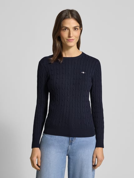 Modelka kobieca nosi Strickpullover mit Label-Detail od GANT, granatowy, strukturalny wzór, dopasowany krój, okrągły dekolt, widok z przodu, ujęcie do pasa.