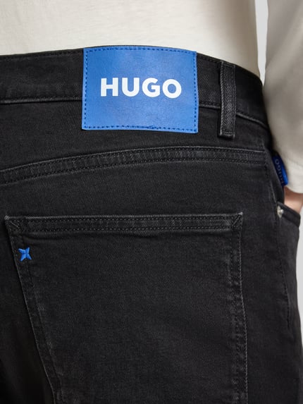 Männermodel trägt Super Slim Fit Jeans aus Baumwoll-Mix Modell 'Zane' von HUGO, schwarze Farbe, Detailaufnahme, Herren Slim Fit Jeans von HUGO Blue.