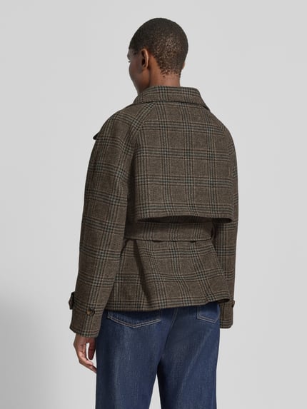 Frauenmodel trägt Jacke mit Stehkragen und Bindegürtel Modell 'Munet' von Neo Noir im braunen Karomuster, Materialmix, Ganzkörperansicht Rückansicht.