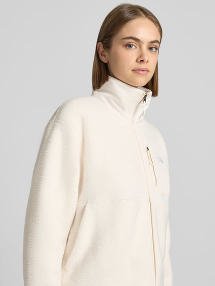Vrouwenmodel draagt Regular fit fleecejack met opstaande kraag Model 'YUMIORI' van The North Face in crèmekleur met gestikt logo, ritssluiting, fleece structuur, context: dames fleecejack, regular fit, ruglengte maat S 58 cm, schouderbreedte 52 cm, borstwijdte 58 cm, mouwlengte 57 cm. Nahaufnahme Oberkörper.