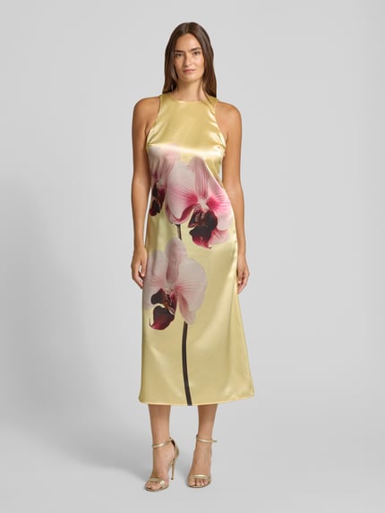 Frauenmodel trägt Cocktailkleid aus Satin mit Motiv-Print von YAS, A-Linie, Rundhalsausschnitt, Midikleid, Ganzkörperansicht von vorne.