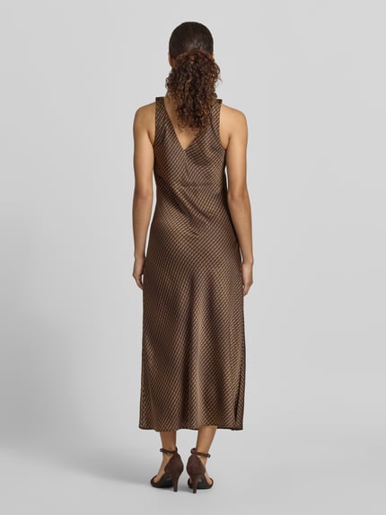 Frauenmodel trägt Midikleid mit V-Ausschnitt Modell 'Qova wave' von Someday aus Satin in Braun mit Wellenmuster, Straight Fit, Ganzkörperansicht Rückansicht. Rückenlänge bei Größe 36: 111 cm, Brustweite bei Größe 36: 45 cm.