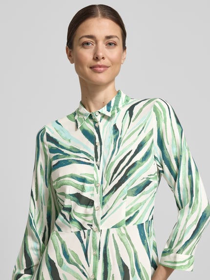 Frauenmodel trägt Hemdblusenkleid aus Reine Viskose Modell 'SAVANNA' von YAS, grün-weiß gemustert, Kentkragen, Knopfleiste, 3/4-Arm, Taillierte Passform, Midikleid, Nahaufnahme Oberkörper. Rückenlänge 135 cm, Brustweite 42 cm, Ärmellänge 49 cm, Größe S.