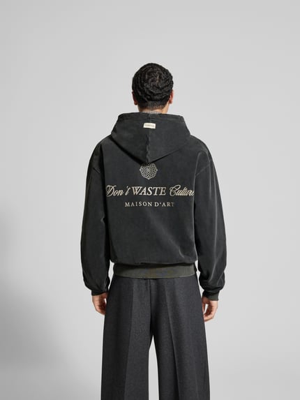 Männermodel trägt Oversized Jeansjacke aus Baumwoll-Mix von Don't Waste Culture, dunkel, elastische Abschlüsse, Ganzkörperansicht Rückansicht.