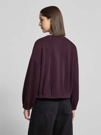 Vrouwenmodel draagt Oversized Sweatshirt met Viskose-Antiel van comma, elastische materiaalmix, met plooien, lange mouwen, oversized fit, donkere paarstint, gladde textuur, Ganzkörperansicht Rückansicht.