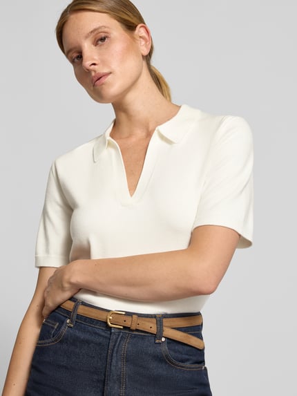 Frauenmodel trägt Regular Fit Poloshirt mit V-Ausschnitt Modell 'Wilma' von GUIDO MARIA KRETSCHMER WOMAN in Creme, glatte Textur, Nahaufnahme Oberkörper. Damen Poloshirt aus Material-Mix mit Woll-Anteil, Label-Detail sichtbar.