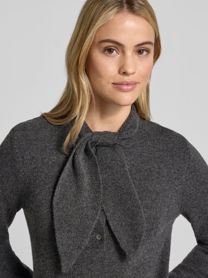 Frauenmodel trägt Strickpullover aus Woll-Mix mit Schluppe und Knopfleiste von Christian Berg Woman, meliertes Dunkelgrau, körpernah, Nahaufnahme Oberkörper. Damen Strickpullover, Rundhalsausschnitt mit Schluppe, kurze Knopfleiste, Woll-Mix, Rückenlänge 56 cm, Ärmellänge 65 cm.
