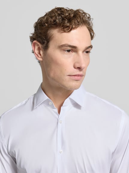 Männermodel trägt weißes Business-Hemd mit Kentkragen Modell 'KENNO' von HUGO, Baumwoll-Elasthan-Mix, Slim Fit, Nahaufnahme Oberkörper.