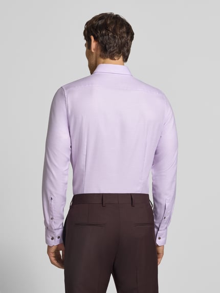 Männermodel trägt Slim Fit Businesshemd aus reiner Baumwolle von Seidensticker in Hellviolett, glatte Struktur, Ganzkörperansicht Rückansicht.