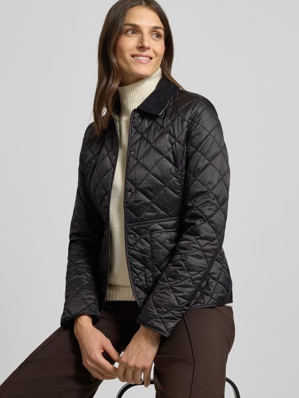 Frauenmodel trägt Steppjacke mit Cordkragen Modell 'Deveron' von Barbour, taillierter Schnitt, schwarze Steppnähte, Ganzkörperansicht von vorne.