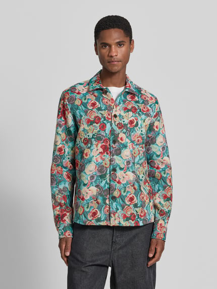 Männermodel trägt Regular Fit Overshirt im Allover-Look von Les Deux aus Baumwoll-Mix mit Kentkragen und Knopfleiste, Rückenlänge 74 cm, Größe M, bunte Farben, florales Muster, glatte Textur, Ganzkörperansicht von vorne.