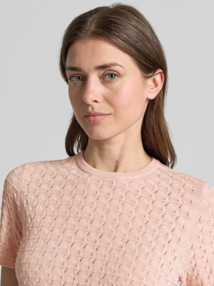 Frauenmodel trägt Strickshirt aus Viskose-Mix mit Rundhalsausschnitt von Jake*s Collection, Strukturmuster, Rosa, Nahaufnahme Oberkörper.