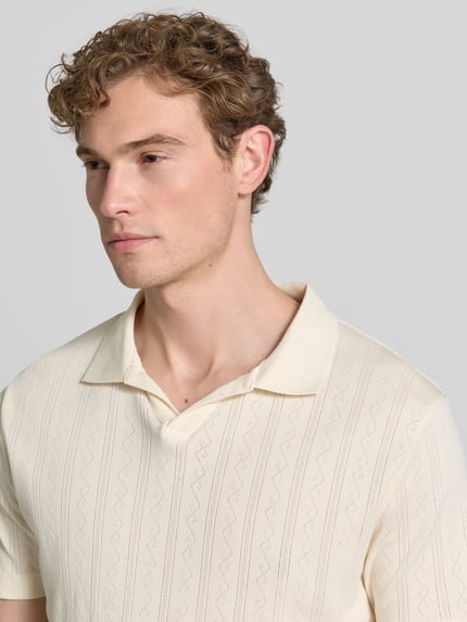 Mannenmodel draagt Regular Fit Poloshirt in Jaquard-Strick van Lindbergh, puur katoen, jacquard-patroon, polokraag, V-hals, labeldetail, ruglengte maat M 73 cm, crèmekleurig met subtiele structuur, Nahaufnahme Oberkörper.