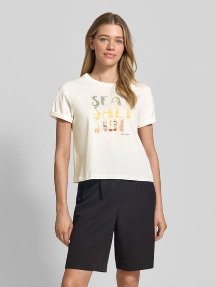 Vrouwenmodel draagt T-shirt met motiefprint van Marc Cain in crème, puur katoen, regular fit, ronde hals, mouwen met omslag, ruglengte maat 36: 51 cm, nahaufnahme bovenlichaam.