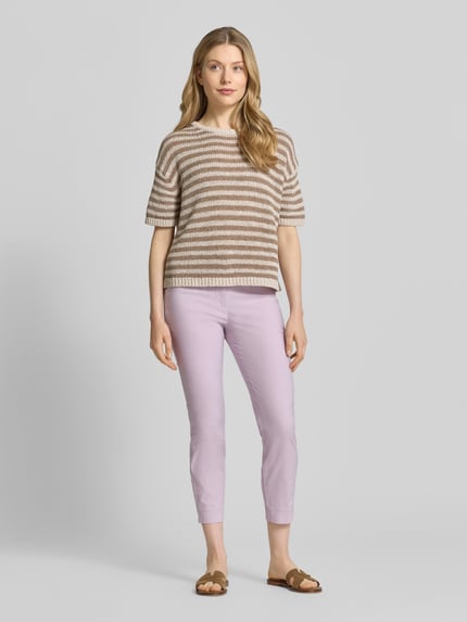 Frauenmodel trägt Slim Fit Stoffhose in verkürzter Passform von Christian Berg Woman aus elastischem Baumwoll-Mix in hellem Flieder, glatte Textur, Knopf- und Reißverschluss, Ganzkörperansicht von vorne.