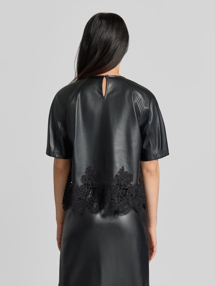 Vrouwenmodel draagt Blusenshirt in lederlook met kanten inzet model 'LONDON' van SUNCOO PARIS, zwart, regular fit, rugaanzicht, KI-modified afbeelding