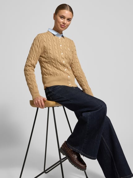 Frauenmodel trägt Slim Fit Strickjacke mit Logo-Stitching von Polo Ralph Lauren in Beige, Rundhalsausschnitt, Knopfleiste, Baumwolle, Nahaufnahme Oberkörper.