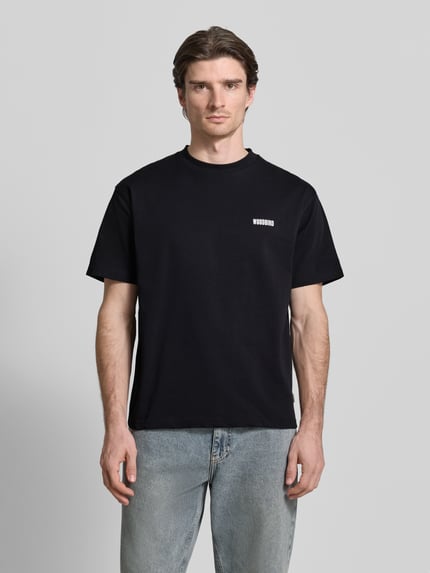 Männermodel trägt schwarzes T-Shirt mit Label-Print Modell 'Baine' von WOODBIRD, reine Baumwolle, Regular Fit, Ganzkörperansicht von vorne