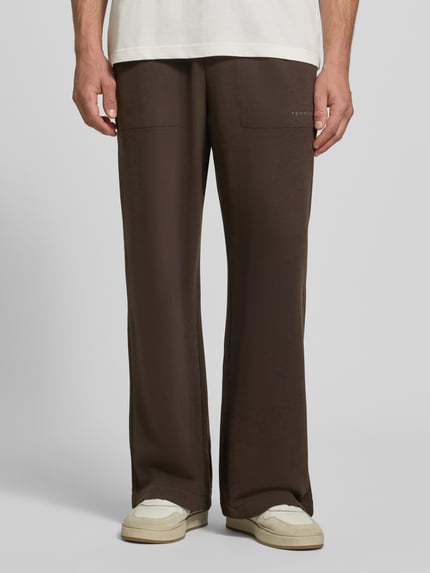 Männermodel trägt Regular Fit Sweathose aus Baumwoll-Modal-Mix von Tommy Hilfiger in Dunkelbraun, glatte Textur, Nahaufnahme Unterkörper, Herren Sweathose von Tommy Hilfiger.