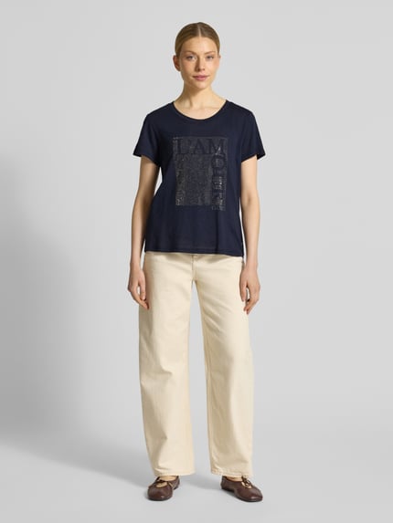 Vrouwenmodel draagt T-shirt met Ziersteinbesatz en ronde hals van monari, mix van katoen en micromodal, regular fit, ruglengte maat 36: 58 cm, donkerblauw, beige broek, Ganzkörperansicht van voren.