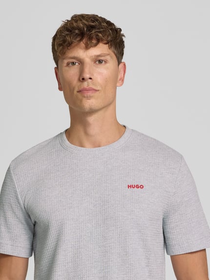 Männermodel trägt hellgraues Herren T-Shirt aus Baumwoll-Mix Modell 'AUSTIN' von HUGO mit feiner Struktur, Nahaufnahme Oberkörper.