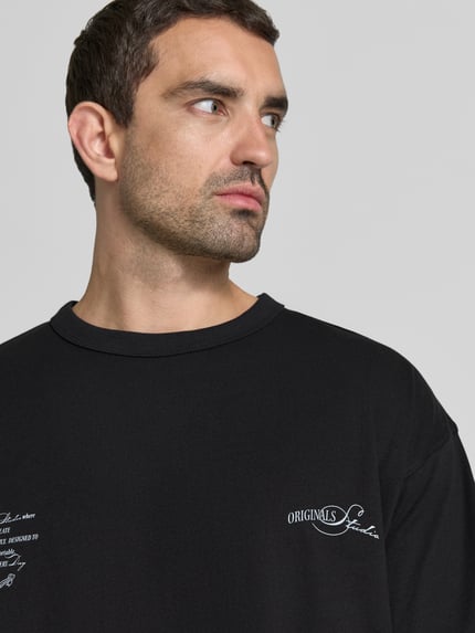 Männermodel trägt Regular Fit T-Shirt mit überschnittenen Schultern von JACK & JONES, Baumwoll-Mix, Rundhalsausschnitt, Nahaufnahme Oberkörper.
