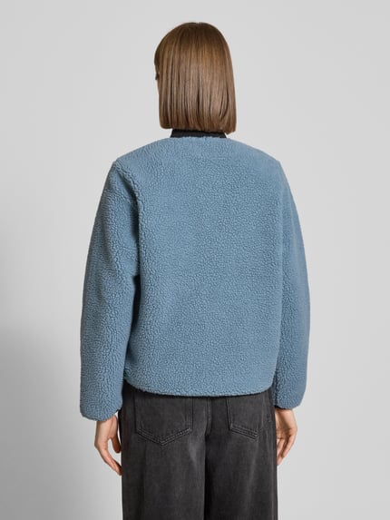 Frauenmodel trägt Fleecejacke im Allover-Look mit Reißverschluss Modell 'Janet' von Carhartt Work In Progress, blaue Textur, lockerer Schnitt, Ganzkörperansicht Rückansicht. Regular Fit, Stehkragen, Label-Detail, Brusttasche, Maße Gr. S: Rückenlänge 63 cm, Schulterbreite 43 cm, Brustweite 52 cm, Ärmellänge 59 cm.