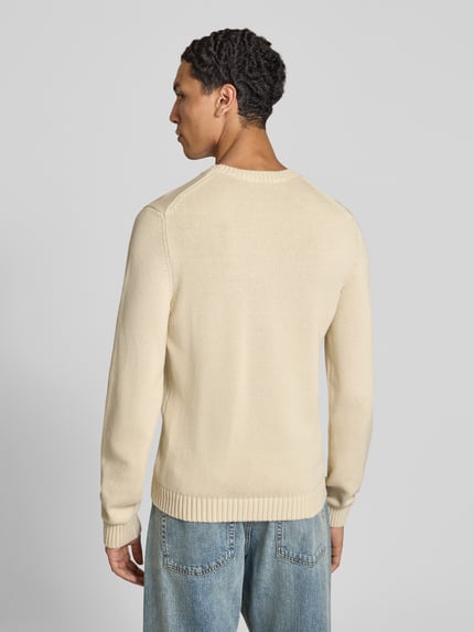 Männermodel trägt Strickpullover mit gerippten Abschlüssen von REVIEW in Beige, reine Baumwolle, gerader Schnitt, Ganzkörperansicht Rückansicht.