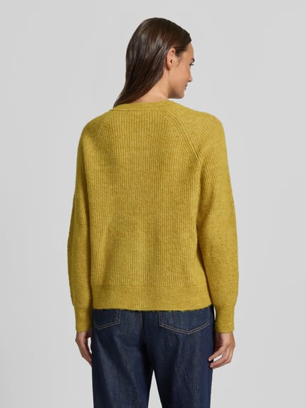 Frauenmodel trägt Relaxed Fit Strickjacke aus Woll-Mix Modell 'LULU' von Selected in Senfgelb, strukturierte Oberfläche, Ganzkörperansicht Rückansicht, Damen Strickjacke.