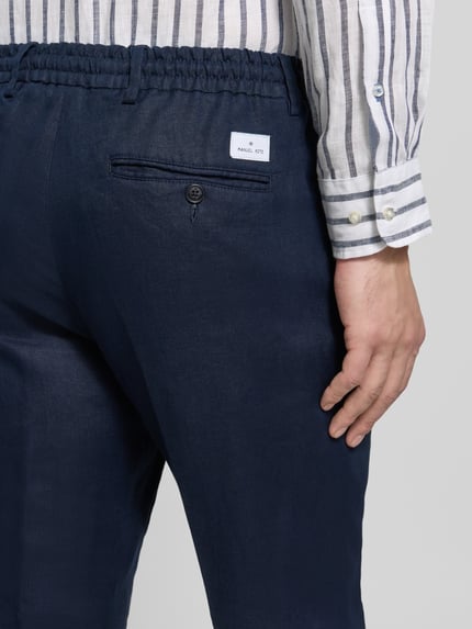 Männermodel trägt Hose mit Bügelfalten und Tunnelzug von Manuel Ritz aus reiner Baumwolle in Dunkelblau, Detailaufnahme Rückansicht.