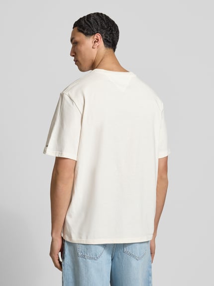 Mannelijk model draagt Regular Fit T-shirt uit puur katoen van Tommy Jeans, look: effen, regular fit pasvorm, labelopschrift, ronde hals, korte mouw, jersey materiaalverwerking, kleur licht crème, achteraanzicht volledige opname.
