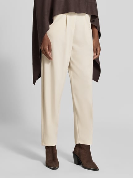 Frauenmodel trägt Relaxed Fit Anzughose mit Bundfalten Modell 'SC-SIHAM 103' von Soyaconcept in Creme, glatte Textur, Nahaufnahme Unterkörper, Damen Anzughose von Soyaconcept.