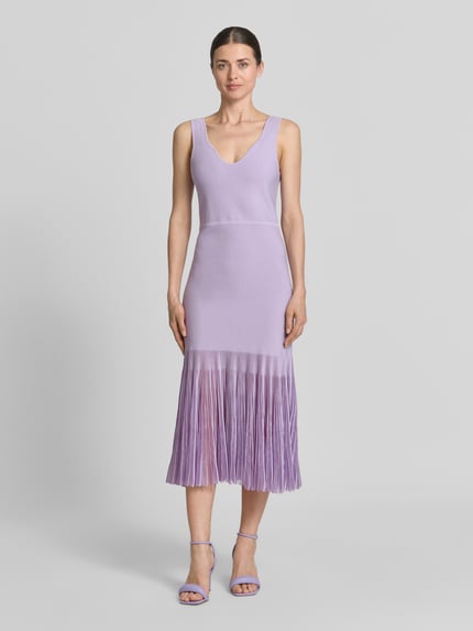 Vrouwenmodel draagt Strickkleid aus Rippstrick van BOSS in lichtpaars, nauwsluitende fit, V-hals, knielang, transparante plisséplooien, volledige lichaamsvoorzijde.